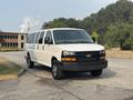A white 2021 Chevrolet Express van with a black front grille and wheels parked on a gravel surface