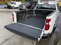 A 2024 Chevrolet Silverado 1500 with an open tailgate and a lined truck bed showcasing its spacious cargo area
