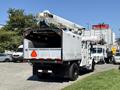 A white 2010 Freightliner M2 106 bucket truck with an extended boom and hydraulic lift mechanism in the back