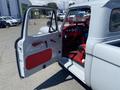 A 1962 Ford 2WHDR with an open door revealing a red interior and dashboard showcasing vintage gauges and controls