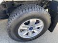 Close-up of a silver alloy wheel with a large all-terrain tire labeled Dynapro AT2 mounted on a 2015 Ford F-150