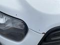 Close-up of a white 2017 Ford Transit van with a focus on the front left headlight and a portion of the hood showing minor blemishes and dirt