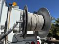A metal hose reel with a coiled hose attached and a valve system on a vehicle designed for industrial use