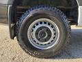 Close-up of a black wheel from a 2024 Mercedes-Benz Sprinter 2500 featuring a silver rim and an all-terrain tire with visible tread patterns