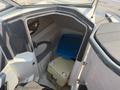 Interior view of a 2013 Larson 238 boat showing a storage compartment with a blue container and a beige cooler