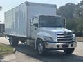 A 2012 Hino 338 truck with a white box cargo area and chrome grille parked on a driveway