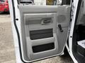 The interior driver's side door of a 2022 Ford E-450 featuring a gray panel with a handle and storage compartment