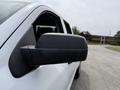 A side view mirror of a white 2018 Chevrolet Silverado 1500 with a black casing
