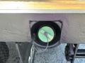 A close-up of a circular trailer hitch receptacle mounted on a metal surface with a green and white connector visible inside