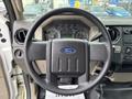 Steering wheel of a 2010 Ford F-550 Super Duty featuring a central Ford emblem and various instrument and control dials in the dashboard behind it