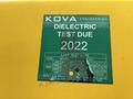 A green inspection sticker on a yellow surface indicating a dielectric test due in 2022 with test dates listed for several months in 2021 and 2022