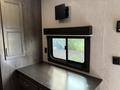 Interior view of a 2021 Jayco Jay Flight showing a window with a black trim and a dark wood surface below it