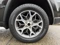 Close-up of a silver alloy wheel from a 2019 Jeep Grand Cherokee featuring a five-spoke design and a rugged all-terrain tire with the brand name Scorpion ATR visible