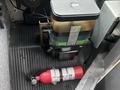 A 2012 Ford Econoline's brake fluid reservoir next to a red fire extinguisher on a rubberized floor mat