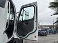 A white 2013 Freightliner 114SD truck with its driver's door open showcasing the interior and side mirror