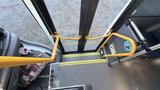 View of the interior steps of a bus with yellow handrails leading to the open exit door