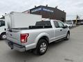 A silver 2015 Ford F-150 truck with a bed cover and four-door configuration parked in a lot