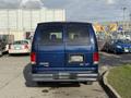 A blue 2011 Ford Econoline van viewed from the rear with tinted windows and a blank license plate holder on the back
