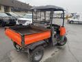 A 2010 Kubota RTV 900 utility vehicle with an orange cargo bed and black cab features large wheels and an open rear area for transporting equipment or materials