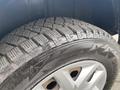 Close-up of a winter tire mounted on a silver wheel displaying deep treads designed for traction on snow and ice