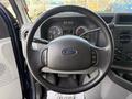 The steering wheel of a 2011 Ford Econoline showing controls and the Ford logo in the center