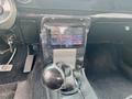 A 1968 Ford Mustang two door convertible showing the gear shift and a modern touchscreen display for audio controls