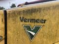 A close-up of a yellow Vermeer Corporation logo featuring a green triangle and the word Vermeer on a machinery component