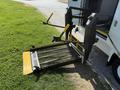 A 2013 Ford Econoline wheelchair lift partially extended with a yellow and black ramp and handrails ready for use