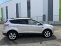 A silver 2015 Ford Escape parked with a sleek design featuring a prominent front grille and five-spoke alloy wheels
