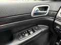 The interior door panel of a 2019 Jeep Grand Cherokee featuring window controls and a sleek handle