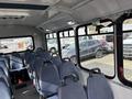 Interior of a 2018 Chevrolet Express featuring multiple blue fabric seats arranged in rows with grab handles attached to the aisle side