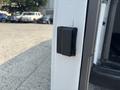 Close-up of a black magnetic latch on the side door of a white 2021 Chevrolet Express