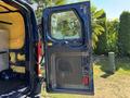 A blue 2016 Ford Transit 150 cargo van with its rear door open revealing a spacious interior and interior insulation material