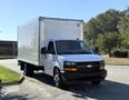 2024 Chevrolet Express white cargo van with a box truck body and black front grille parked with the driver side facing forward