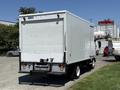 A 2012 Isuzu NPR HD box truck with a white exterior and a rear loading door