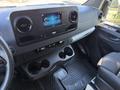 Interior view of a 2023 Mercedes-Benz Sprinter 2500 featuring a central touchscreen display and cup holders with a textured floor mat below
