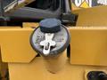 Close-up of a fuel cap from a 2012 Caterpillar 980 featuring a blue cap with a clip and the Caterpillar logo on a yellow body