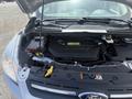 Engine compartment of a 2014 Ford Escape showing the engine battery and various components with some labels and a dipstick visible