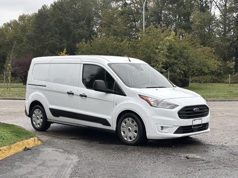 A white 2019 Ford Transit Connect van parked with its side facing the viewer showcasing its compact design and sliding side door