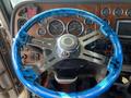 A blue and silver steering wheel in a 2009 Peterbilt Highway truck featuring a chrome center and a marble-like design on the outer rim