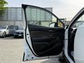 A white 2021 Toyota C-HR with the front door open showcasing the interior door panel and handle
