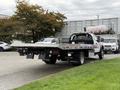 A 2022 Ford F600 flatbed truck with a silver flatbed and black chassis parked with a tow hitch and dual rear wheels