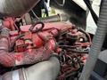 Close-up of a red engine with various hoses and wires visible, featuring exposed mechanical components typical of a 2010 Autocar Xpeditor