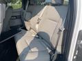 A gray cloth rear seat of a 2016 Ford F-150 with seat belts and a folding armrest