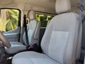 Interior of a 2016 Ford Transit 150 showing two gray cloth bucket seats with seat belts and armrests