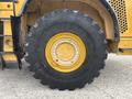 Close-up of a large tire on a 2012 Caterpillar 980 showcasing its deep treads and yellow rim with multiple bolt holes