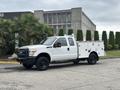 A 2013 Ford F-250 SD work truck in white with a utility bed and black rims parked at an outdoor location