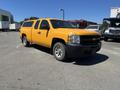A 2013 Chevrolet Silverado 1500 pickup truck painted bright yellow with a truck bed cap and alloy wheels parked on a surface