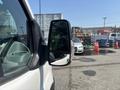A 2019 Ford Transit 350 van featuring a side mirror with a black housing and a white body visible from the front driver's side perspective