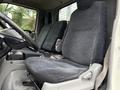 Interior view of the driver's seat and passenger seat in a 2015 Hino 195 with fabric upholstery and a simple dashboard layout